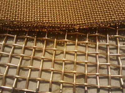 Several pieces of brass crimped wire mesh on the ground.